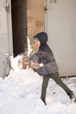 Bir çocuk garajın yanındaki karı kürekle temizliyor. Yılbaşı havası. Kış zamanı. Kar tatili. Kar yağışıweather condition