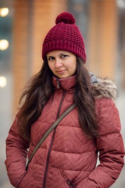 Kırmızı şapkalı bir kadının kış portresi. Noel zamanı. Kar yağışı, soğuk. Mutlu yıllar. Kış tatilleri karlı şehir.