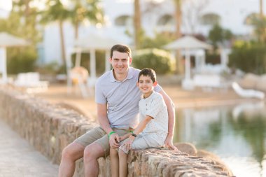 İnsanlar ve çocuklar gölün sahilinde oturuyorlar. Baba ve oğul. Babalar Günü. Aile tatili. Tatil