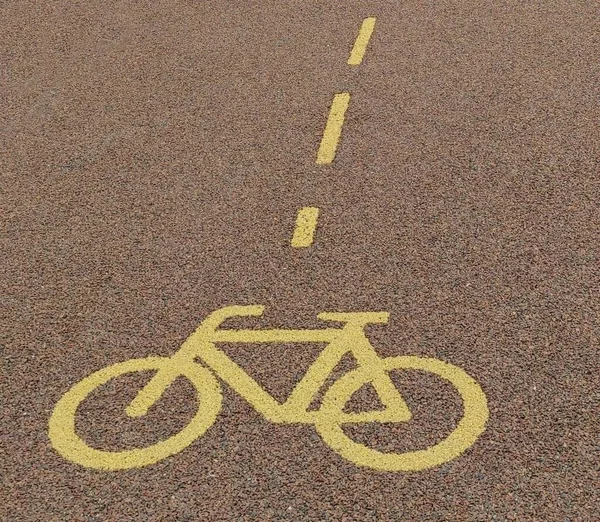 Road sign for cycle on the asphalt. Yellow painted sign for bikes on bicycle lane. Turning road.