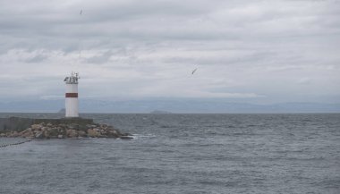 Türkiye 'nin İstanbul kentinde bulutlu bir günde deniz fenerinin manzarası. Dalgakıranlardaki deniz fenerlerinden biri. Reklam pankartı ya da fotokopi alanı olan poster. Uçan martılar. Boğaz Boğazı, Marmara Denizi, Karadeniz.