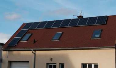 Modern çatı pencereleri ve güneş panelleri olan kırmızı kiremit çatı. Ev için çevre dostu alternatif enerji. Banliyöde yaşayan bir aile evi. Ev güneş paneli.