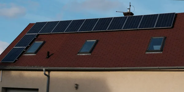 Red tile roof of home with modern roof windows and solar panels. Eco-friendly alternative energy for house. Residential family house suburban. Home solar panel.