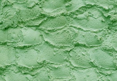 Dondurma dokusu. İştah açıcı ve yarım küreler halinde dizilmiş fıstıklı dondurmanın lezzetli arka planı. Alçıdan yapılmış bir duvarın desenli arka planı. Uzayı kopyala Kapatın. Ev yapımı Gelato