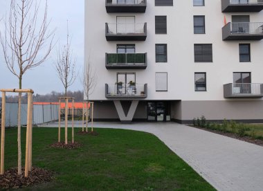 Modern tall condominium apartments building. View on the windows and balconies with flowers of a typical concrete apartment building. Entrance to the residential building. Real estate concept. 