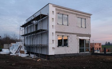 Tamamlanmamış iki katlı bir ev, tipik modern bir banliyö evi. Kısmen inşa edilmiş bir ev. İnşaat alanı, eksik inşaat ve çöp. Enerji tasarrufu için dış görünüşün yalıtımı.