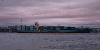 MAERSK Hattı konteynır gemisi ISTANBUL / Türkiye 'deki Boğaz' dan geçiyor - Ocak 2021. Maersk dünyanın en büyük konteyner gemisi operatörüdür. Gün batımı gökyüzü.