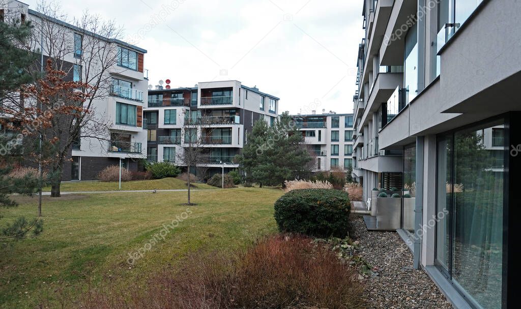 Modern condominium apartments building. View on the windows and balconies of typical concrete apartment building. Green meadow and garden at the house. Real estate, residential apartments and offices