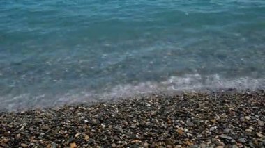 Deniz sıçraması, köpüklü dalgalar. Su dalgaları yüzeyi, arka planda fotokopi alanı. Dalgalı deniz yüzeyine yakın çekim. Su dalgalanması. Deniz yüzeyi. Okyanus dalgası. Çakıl taşı plajı.