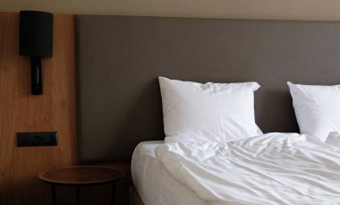 Yatak odasının boş komodini, okuma lambasını ve modern iç dizayn evi ya da otelde USB soketini içeren yakın plan bir parçası. İki beyaz yumuşak yastık ve battaniye, şık rahat mobilyalar.. 