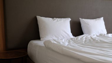 Yatak odasının boş komodini, okuma lambasını ve modern iç dizayn evi ya da otelde USB soketini içeren yakın plan bir parçası. İki beyaz yumuşak yastık ve battaniye, şık rahat mobilyalar.. 