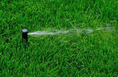 Otomatik bahçe sulama sistemi çimleri suluyor. Fıskiye sulama sisteminden ayarlanabilir başlıklı su tasarrufu. Çim sulama, bahçıvanlık, futbol sahaları veya golf sahaları için otomasyon.