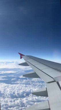 View from airplane window. Beautiful cloudscape with blue sky. Wonderful panorama above white clouds as seen through window of an plane. Traveling by air concept. 