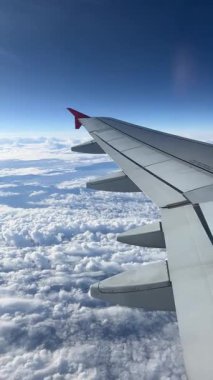 View from airplane window. Wonderful panorama above white clouds as seen through window of airplane. Beautiful cloudscape with blue sky. Traveling by air concept.