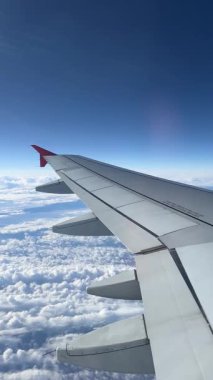 View from airplane window. Beautiful cloudscape with blue sky. Wonderful panorama above white clouds as seen through window of an plane. Traveling by air concept. Selective focus.