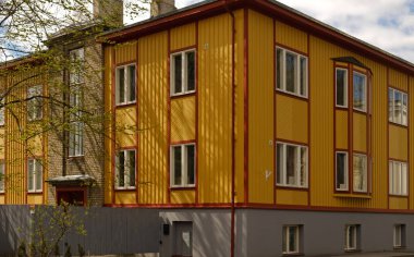 Kırmızı çerçeveli, parlak sarı çok katlı bir bina ve çok sayıda beyaz çerçeveli pencereler. Canlı bir kentsel mimari zemin. Estonya 'da geleneksel şehir mimarisi