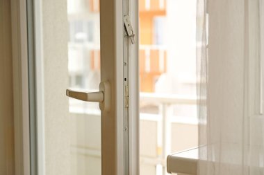 Açık beyaz bir balkon kapı kolunun yakın çekim perdesi yavaşça dalgalanır. Stossluften - şok havası, temiz hava..