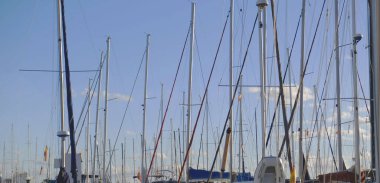 Açık mavi gökyüzüne karşı yelkenli direkleri olan sakin bir marina. Seyahat, boş zaman, yat yaşam tarzı ve deniz kenarı turizmi için..