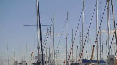 Açık mavi gökyüzüne karşı yelkenli direkleri olan sakin bir marina. Seyahat, boş zaman, yat yaşam tarzı ve deniz kenarı turizmi için..