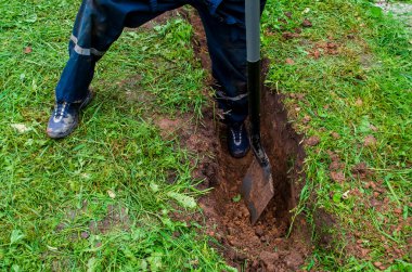 Çalışan adam kanalizasyonun altında siper kazıyor.