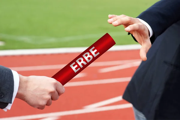 Starting the legacy - businessman passes the baton with the German word Erbe — Stockfoto