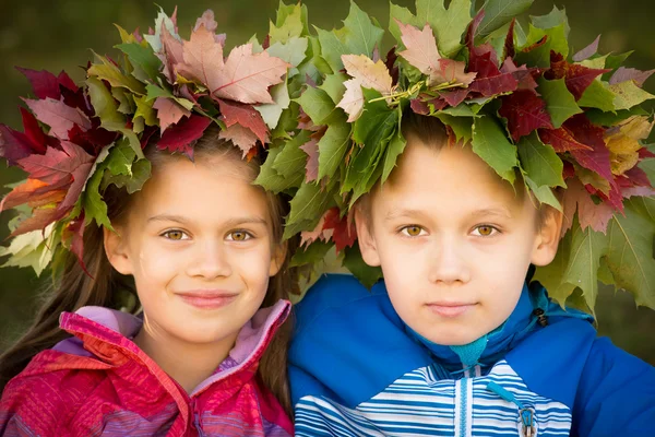 Pojke och en flicka klädd i krans av lämnar — Stockfoto