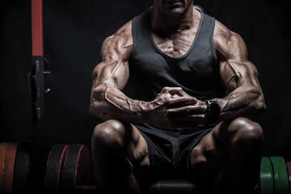 薄暗い光に座って体に静脈を持つ非常に筋肉のボディビルダーの男 ジムトレーニング フィット感とリーンボディ — ストック写真