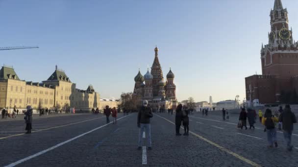 MOSCA, RUSSIA - 5 DICEMBRE 2020: Time Lapse of Man in Mask Standing Still su Red Square e utilizzando smartphone durante la pandemia di Coronavirus Covid-19 in inverno. Cremlino di Mosca e folla di persone. — Video Stock