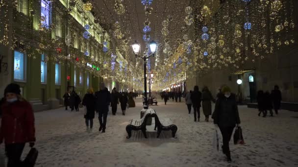 モスクワ、ロシア- 2020年12月25日:イルミネートされたニコライスカヤ歩行者天国通り。冬の夜に人を歩く。クリスマス休暇。モスクワロシア — ストック動画