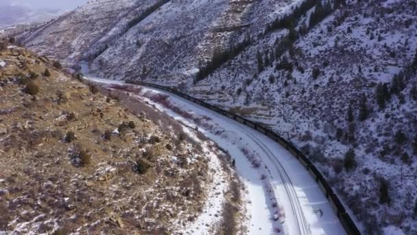 Грузовой поезд и Снежные горы зимой. Юта, США. Вид с воздуха — стоковое видео