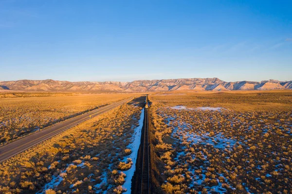 Kışın Sunset 'te çöl, yük treni, yol ve dağlar. Utah, ABD. Hava Görünümü