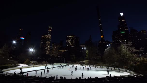 NEW YORK CITY, USA - JANUARI 22, 2021: Mensen die 's avonds schaatsen op de Wollman ijsbaan in Central Park. Stadsgezicht van de stad — Stockvideo