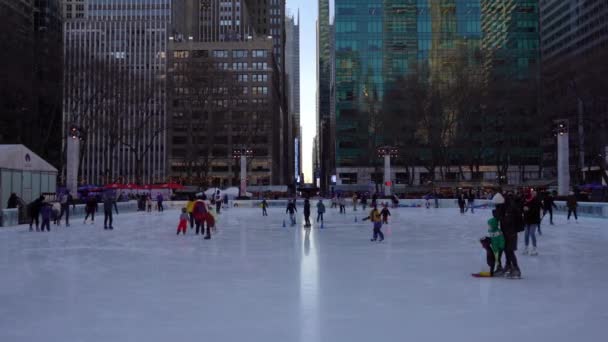 NEW YORK CITY, USA - JANUÁR 23, 2021: Maszkot viselő emberek korcsolyáznak a jégpályán a manhattani Bryant Parkban a téli napon — Stock videók