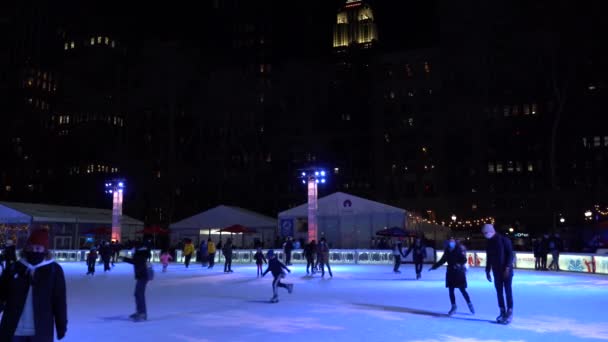 NEW YORK CITY, USA - JANUÁR 23, 2021: Maszkot viselő emberek korcsolyáznak a jégpályán a manhattani Bryant Parkban téli esténként a Covid-19-es világjárvány idején — Stock videók