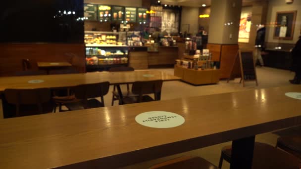 ЧИКАГО, США - 27 января 2021 года: таблица временно закрыта знак в кафе Starbucks во время коронавирусной пандемии. Ужин на вынос и ужин на открытом воздухе. Вид извне через окно. Отражение автомобилей — стоковое видео