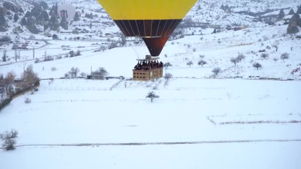 CAPPADOCIA, TURCHIA - 10 APRILE 2021: Cesto mongolfiera con persone in Cappadocia nevosa nella mattina d'inverno. Tacchino. Vista aerea — Video Stock