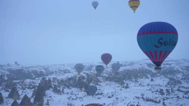 KAPPADOCIA, TÜRKEI - 10. April 2021: Heißluftballons im verschneiten Kappadokien am Wintermorgen. Türkei. Luftaufnahme — Stockvideo