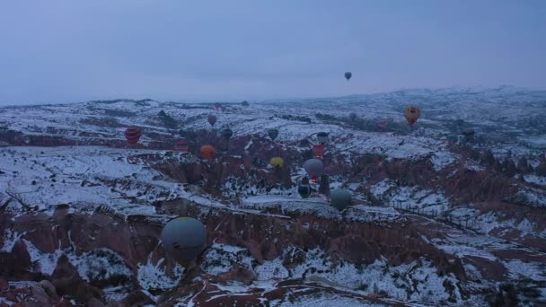 CAPPADOCIA, TURQUÍA - 10 DE ABRIL DE 2021: Globos de aire caliente en Capadocia nevada en la mañana de invierno. Pavo. Vista aérea. Drone está orbitando — Vídeo de stock