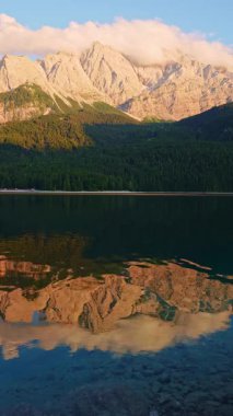 Eibsee Gölü, Ormanlı Dağ yamaçları ve Sunset 'te Zugspitze Massif. Suyun yansıması. Bavyera, Almanya. Dikey Video