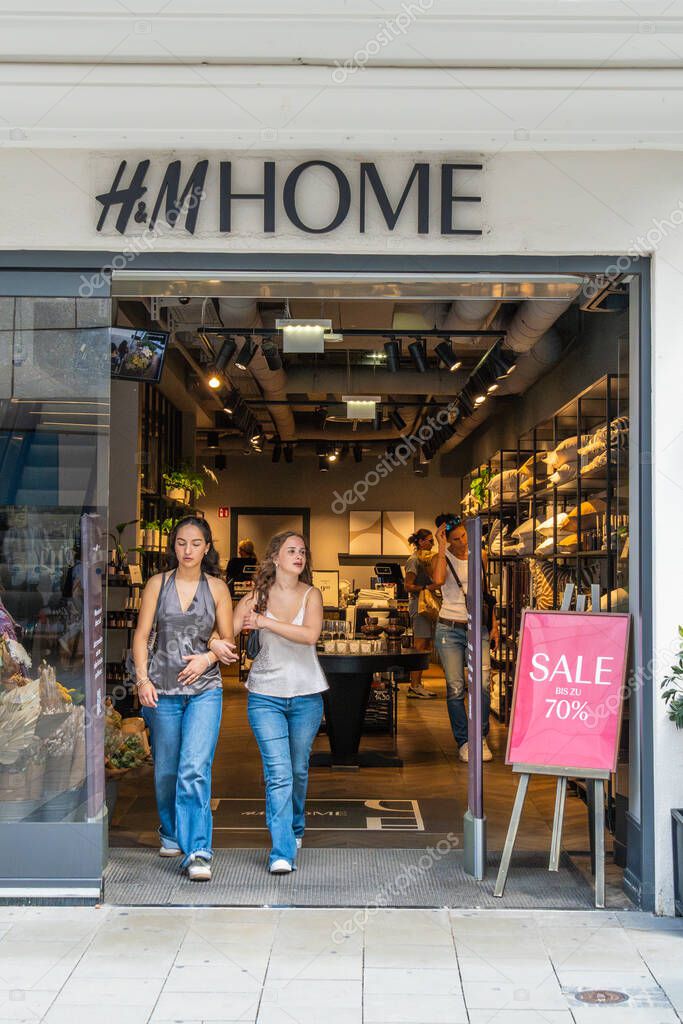 MUNICH, GERMANY - JULY 14, 2025: H and M Home Store Entrance. Storefront with Sale Sign. Two Customer Women Leaving the Shop. Munich, Bavaria, Germany