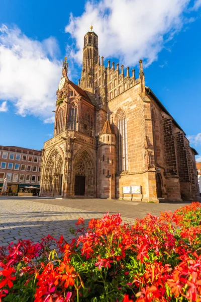 Sunny Summer Evening 'deki Frauenkirche Kilisesi Batı Cephesi. Ön planda kırmızı çiçekler. Nuremberg, Franconia, Almanya