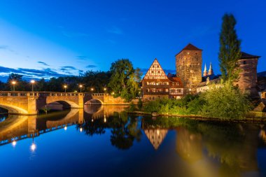 Geceleyin Aydınlanmış Tarihi Eski Şehir. Weinstadel Binası, Maxbrucke Köprüsü, Henkerturm Kulesi. Pegnitz Nehri. Sudaki yansıma. Nuremberg, Franconia, Almanya. Geniş Görüntü