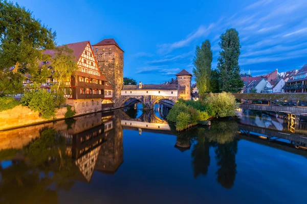 Akşam Alacakaranlığı 'nda Aydınlanmış Tarihi Şehir. Weinstadel Binası, Henkerbrucke ve Maxbrucke Köprüsü, Henkerturm Kulesi. Pegnitz Nehri. Sudaki yansıma. Nuremberg Franconia Almanya 'sı. Geniş Görüntü