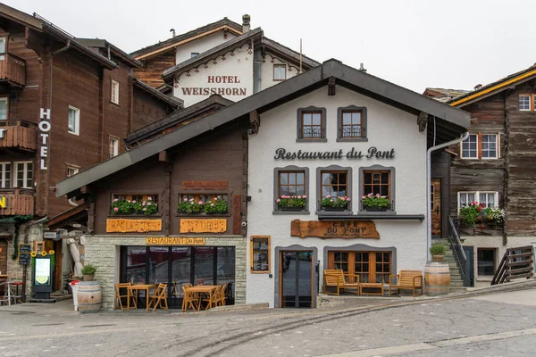 ZERMATT, SWITZERLAND - OCTOBER 20, 2025: Restaurant du Pont and Hotels in Autumn on Cloudy Day. Zermatt, Valais, Switzerland