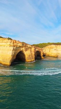 Güneşli bir günde Benagil Mağarası, Kayalıklar ve Atlantik Okyanusu. İHA atışı. Algarve, Portekiz. Yörüngede. Dikey Video