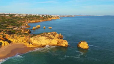Güneşli bir günde Arrifes Sahili, Burnu, Kayalıkları, Sahili ve Atlantik Okyanusu. Yeşil Ağaçlar. Havadan çekim. Algarve, Portekiz. Yörüngede
