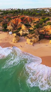 Güneşli bir günde Paradinha Sahili, Kayalar ve Atlantik Okyanusu. Yeşil Ağaçlar. Hava görüntüsü. Algarve, Portekiz. Yörüngede. Dikey Video