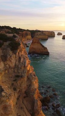 Marinha Sahili, Deniz Yığınları, Kayalıklar ve Gündoğumunda Atlantik Okyanusu. Altın Saat. İHA atışı. Algarve, Portekiz. İlerleme kaydediyoruz. Dikey Video
