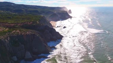 Sahil şeridi, yeşil dağlar ve tepeler güneşli bir günde. Hava görüntüsü. Atlantik Okyanusu, Portekiz. İleriye Taşınma