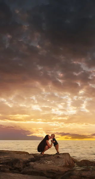 Moeder en baby op het strand na zonsondergang — Stockfoto